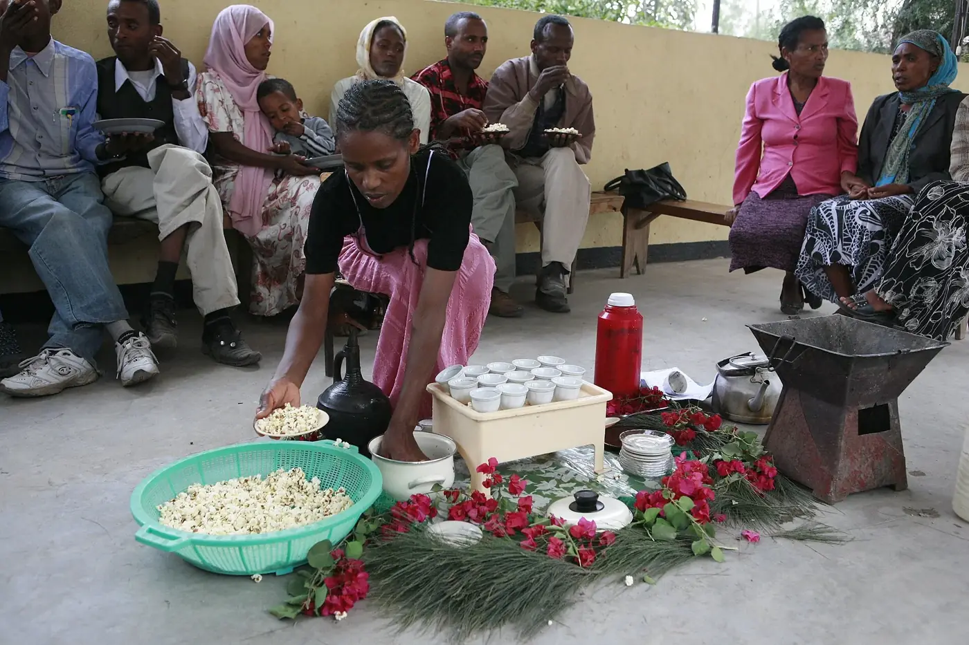 A woman preparing coffee at an Ethiopian coffee ceremony while others look on